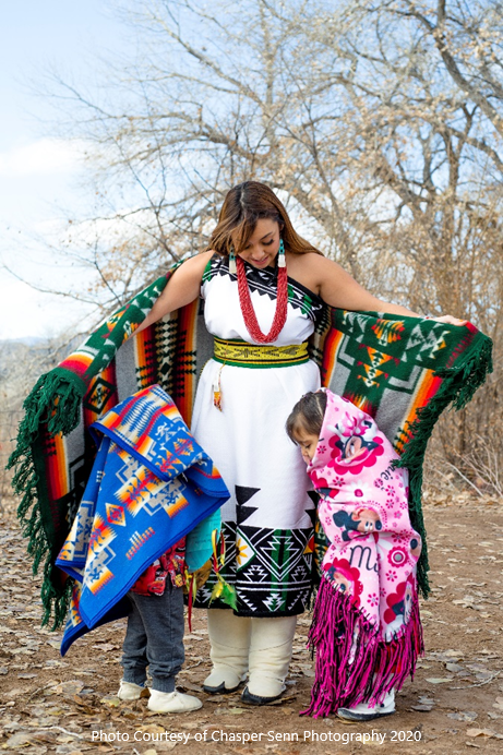 Pueblo mother dressed in traditional clothing with two small children